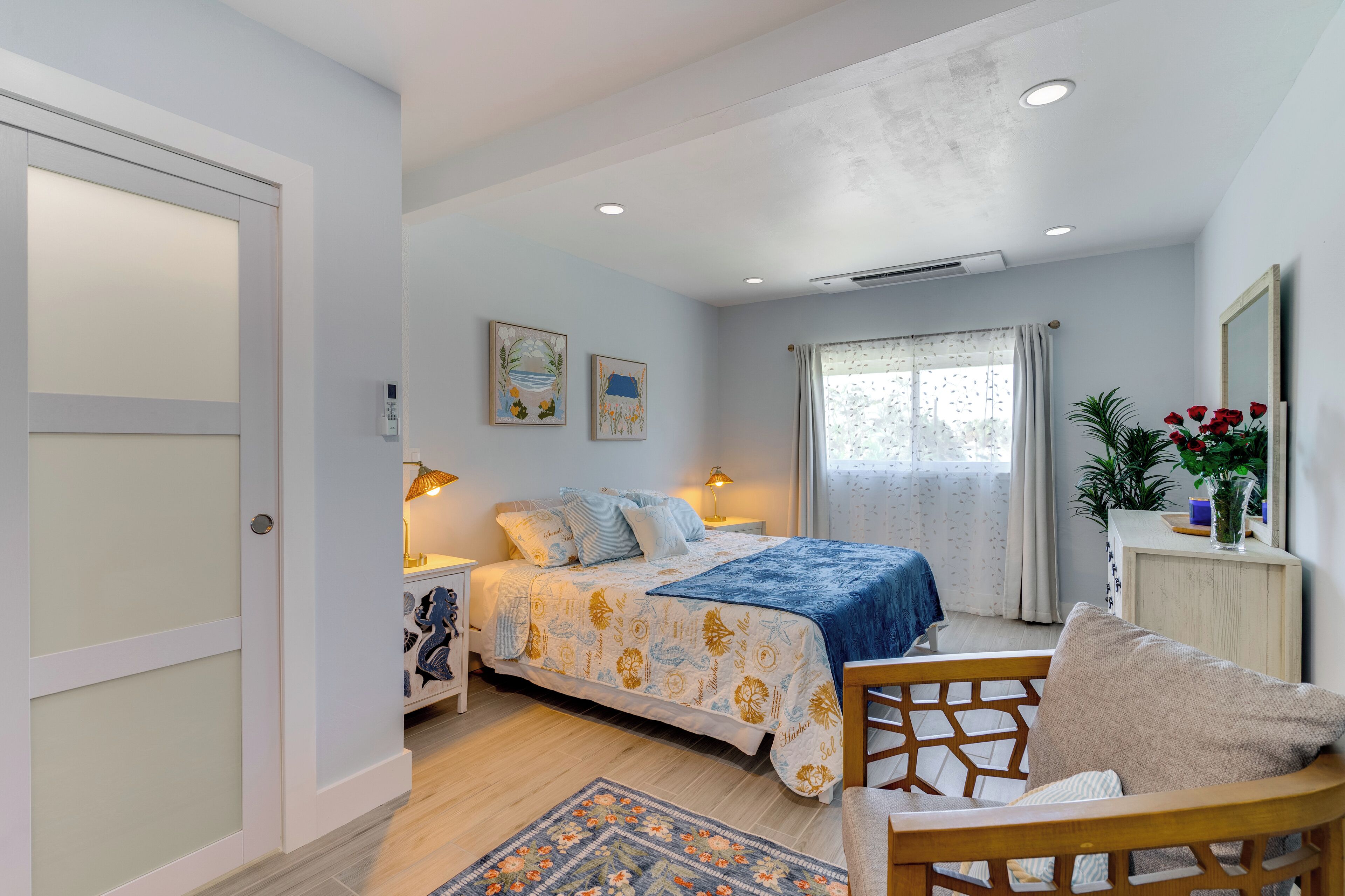 A bedroom with a bed, bedside tables, a chair, a rug, and a window with curtains.