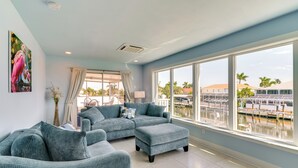 A spacious living room with a large window, a sectional sofa, and a view of a marina. - Canalfront St James City Home w/ Unique View (Saint James City)