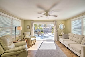 A living room with a beige sofa, a recliner, a ceiling fan, and a view through a glass door to an outdoor patio. - Canalfront Punta Gorda Home With Private Dock! (Punta Gorda)