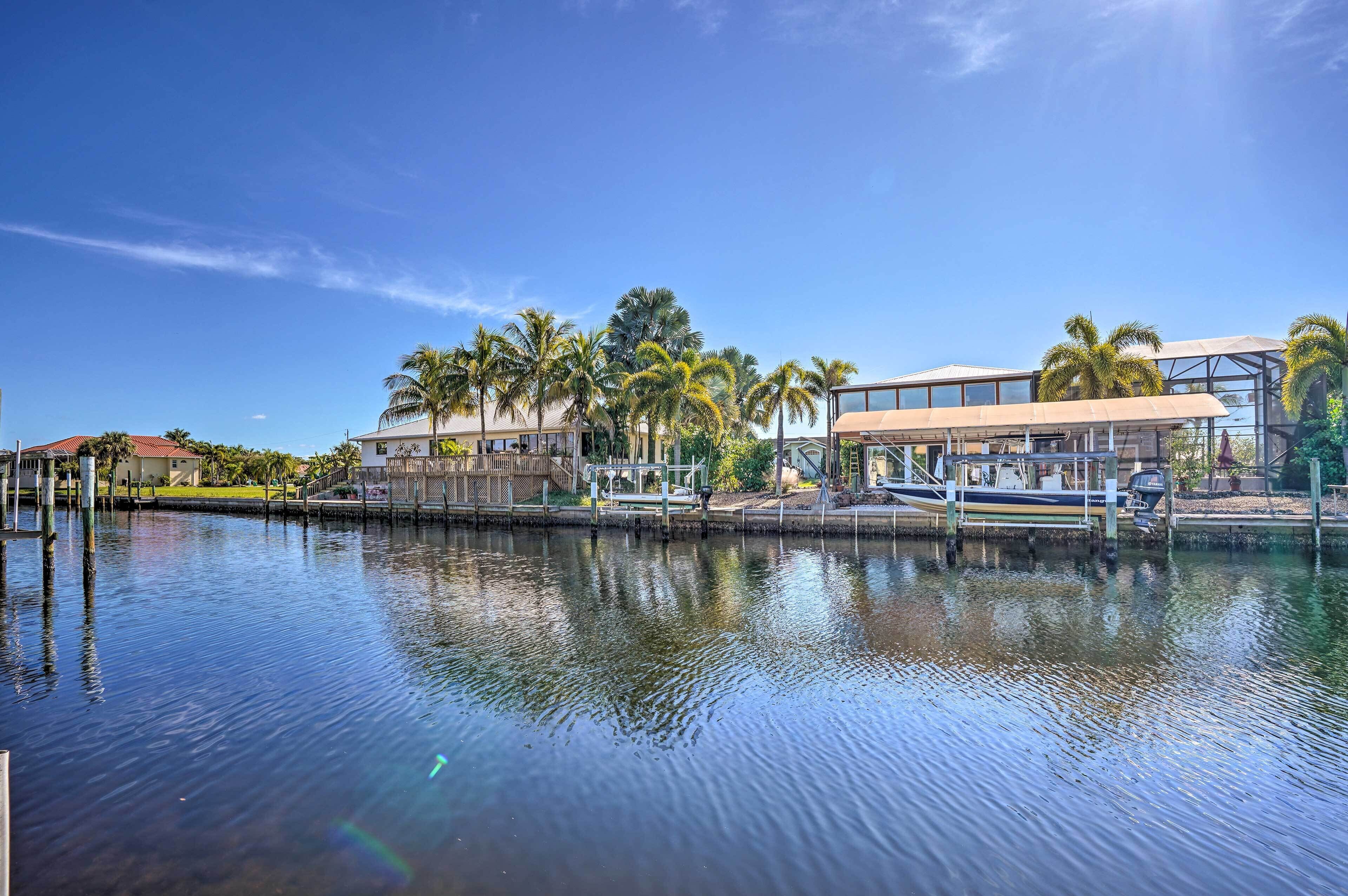 A waterfront property with a dock, palm trees, and a modern building with large windows.