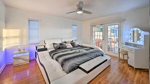 A bedroom with a large bed, a ceiling fan, a vanity with lights, and a view through the window. - Canal-front Cape Coral Home w/ Patio & Grill! (Cape Coral)