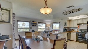 A spacious kitchen with white cabinets, a dining table with chairs, and a large window providing natural light.