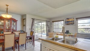A modern kitchen with a dining area, large windows, and a view of the outdoors.