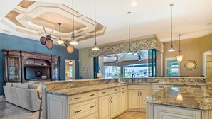 A spacious kitchen with a large island, white cabinetry, and a modern ceiling design. - 'casa Getaway' Cape Coral Home w/ Lanai & Pool! (Cape Coral)