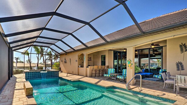 A covered outdoor pool area with a clear view of the pool, lounge chairs, and a patio with a table and chairs. - 'casa Getaway' Cape Coral Home w/ Lanai & Pool! (Cape Coral)