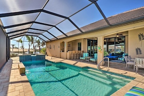 A covered outdoor pool area with a clear view of the pool, lounge chairs, and a patio with a table and chairs. - 'casa Getaway' Cape Coral Home w/ Lanai & Pool! (Cape Coral)