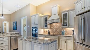 A modern kitchen with white cabinetry, stainless steel appliances, and a granite countertop. - 'casa Getaway' Cape Coral Home w/ Lanai & Pool! (Cape Coral)