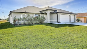 A modern single-story house with a garage, a well-maintained lawn, and a clear sky. - Central Cape Coral House w/ Private Screened Pool! (Cape Coral)