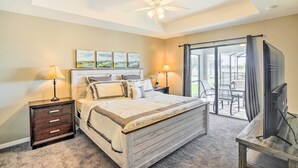 A bedroom with a bed, two bedside tables with lamps, a ceiling fan, a TV, and a sliding glass door to a balcony. - Central Cape Coral House w/ Private Screened Pool! (Cape Coral)