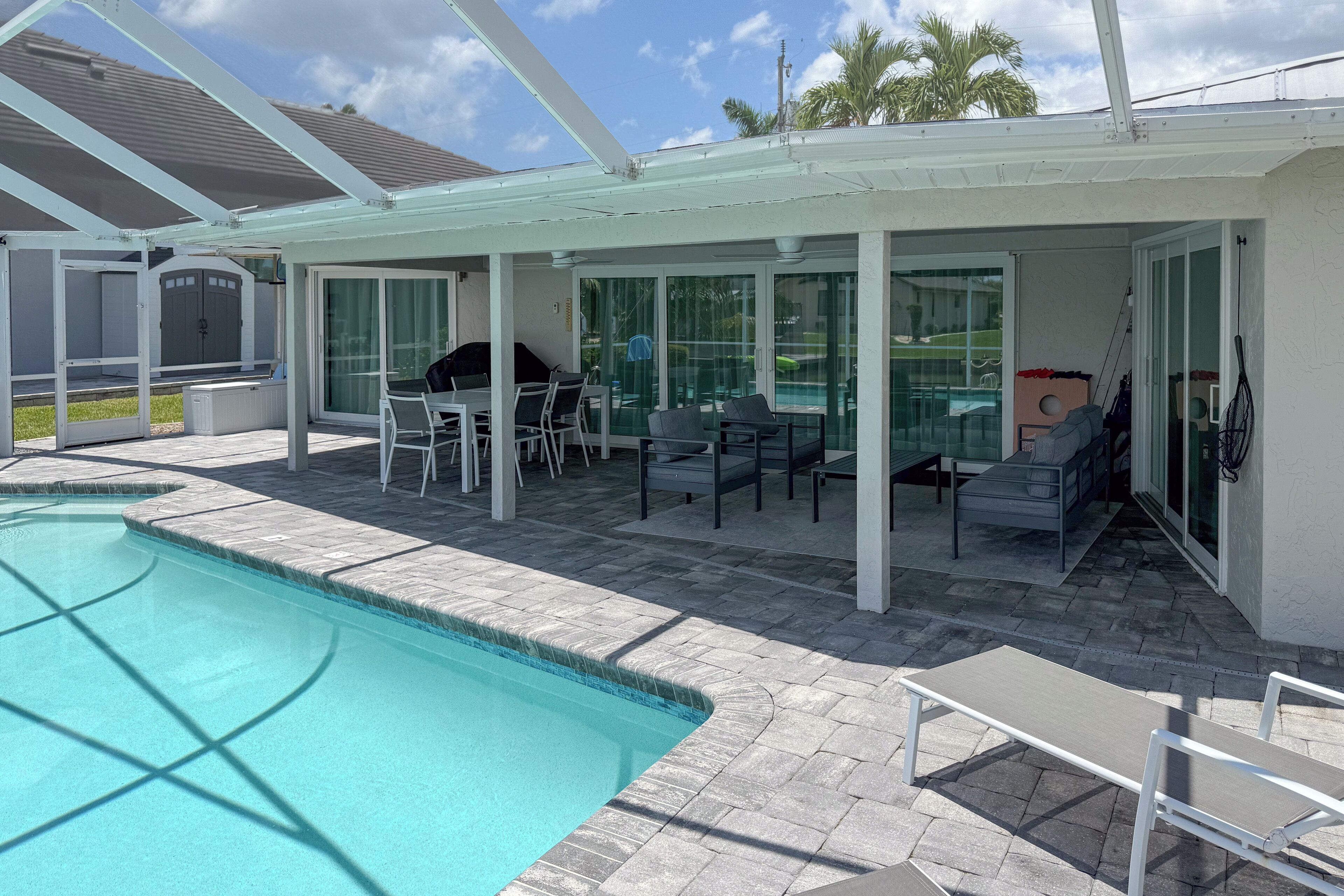 A covered outdoor area with a pool, patio furniture, and a barbecue grill.