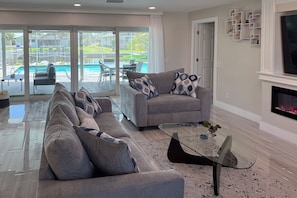A modern living room with a sectional sofa, a glass coffee table, and a fireplace.