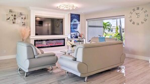 Ein modernes Wohnzimmer mit Kamin, großem Flachbildfernseher und bequemer Couch.