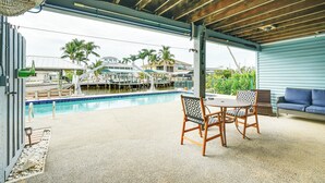 Ein Poolbereich im Freien mit einer überdachten Terrasse, einem Tisch und Stühlen.