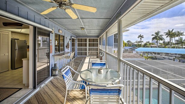 Ein überdachter Balkon mit Deckenventilator, eine Glastür zu einer Küche und Blick auf den Hafen.