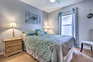 Um quarto com uma cama, duas mesas de cabeceira com luminárias, uma cadeira e uma janela com cortinas.