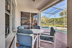 Um alpendre coberto com mesa e cadeiras, uma piscina e vista para o exterior.