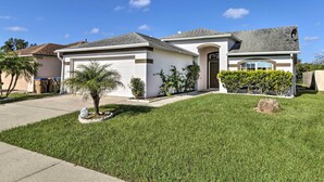 A single-story house with a garage, a small front yard with a palm tree, and a satellite dish on the roof. - Charming Kissimmee Retreat w/ Pool & Lanai! (Kissimmee)