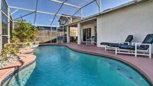 A swimming pool with a glass enclosure, surrounded by lounge chairs and a wooden fence. - Charming Kissimmee Retreat w/ Pool & Lanai! (Kissimmee)