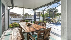 A covered patio with a wooden table and chairs, a grill, and a view of the neighborhood. - Chic Cape Coral Oasis w/ Pool: 5 Mi to Beach! (Cape Coral)