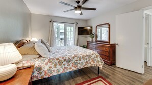 A bedroom with a bed, a ceiling fan, a dresser, a mirror, and a window with curtains. - Charming Tallahassee Townhouse ~ 3 Mi to Fsu! (Tallahassee)