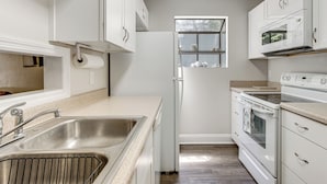 A kitchen with white cabinets, a stainless steel sink, a built-in oven, and a microwave. - Charming Tallahassee Townhouse ~ 3 Mi to Fsu! (Tallahassee)