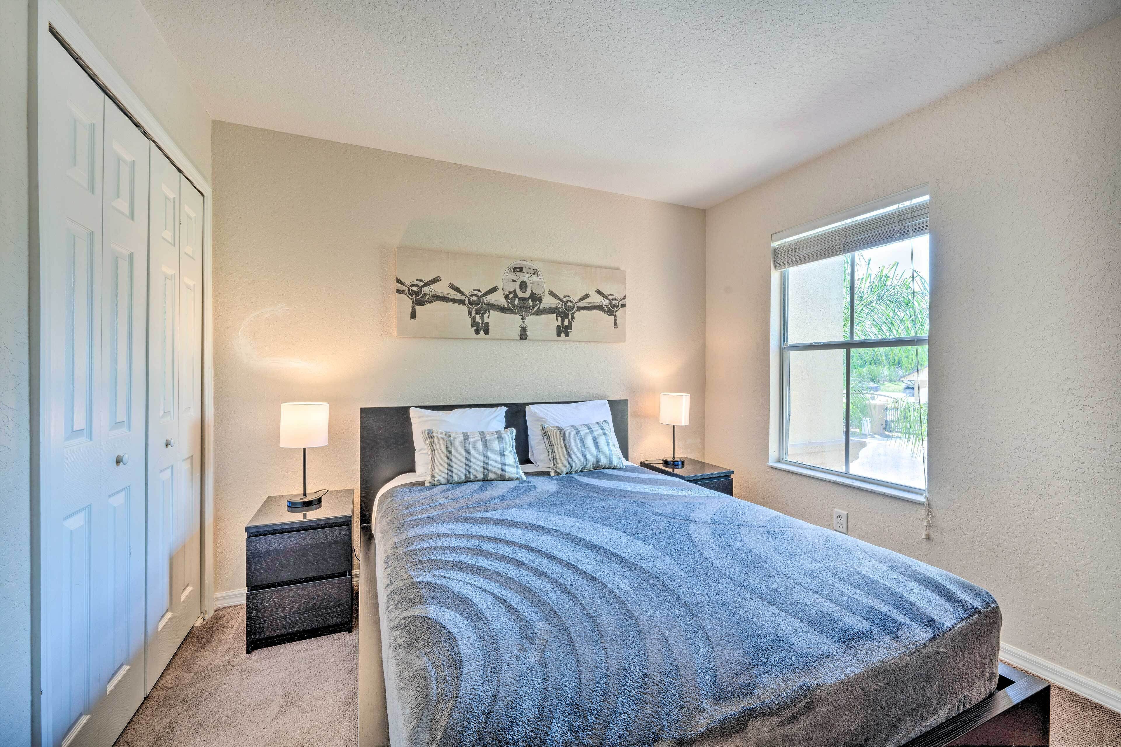 A bedroom with a bed, two bedside tables, a nightstand, a window, and a door.