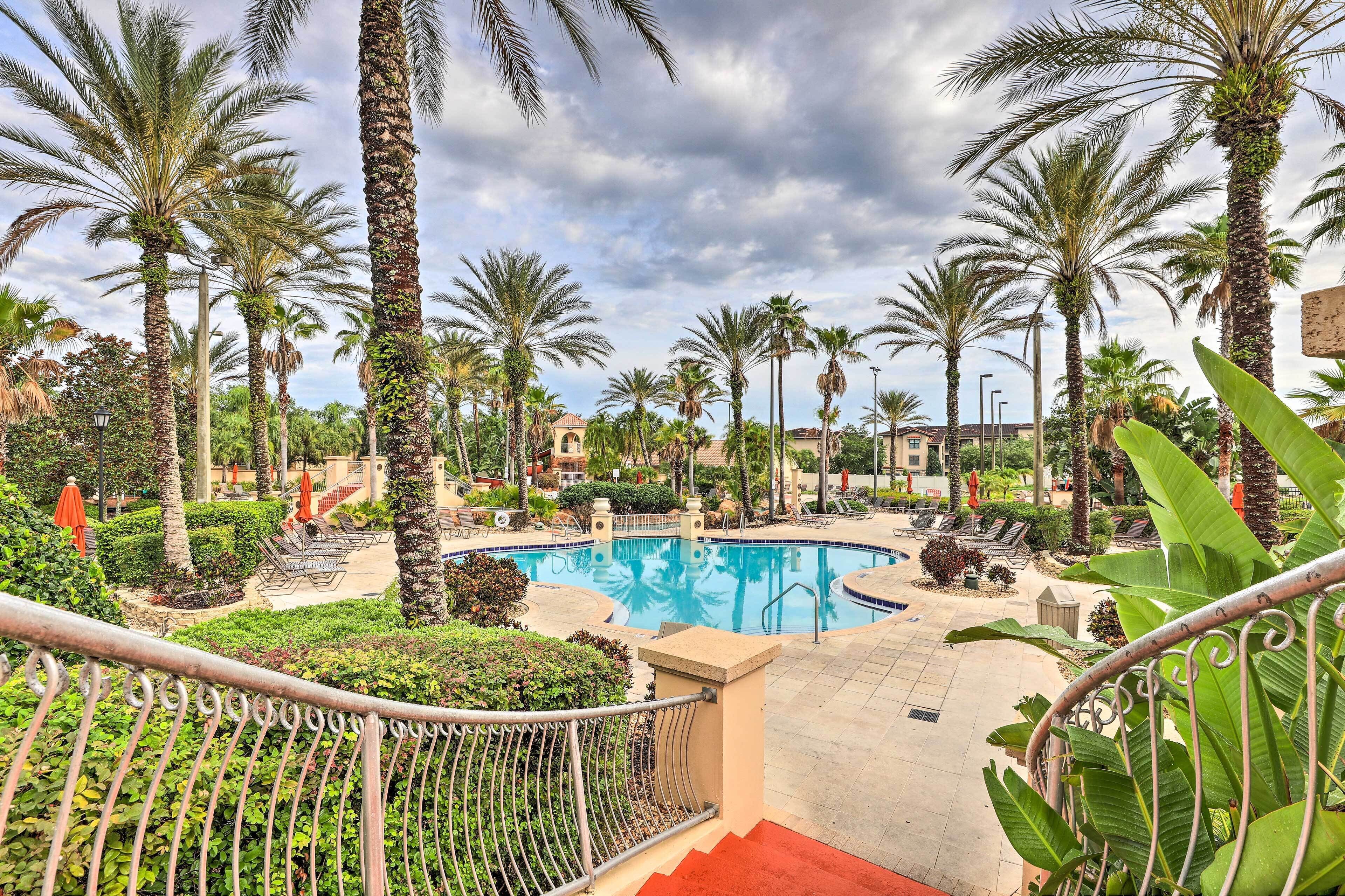 A pool area with palm trees and a red carpet leading to a pool.