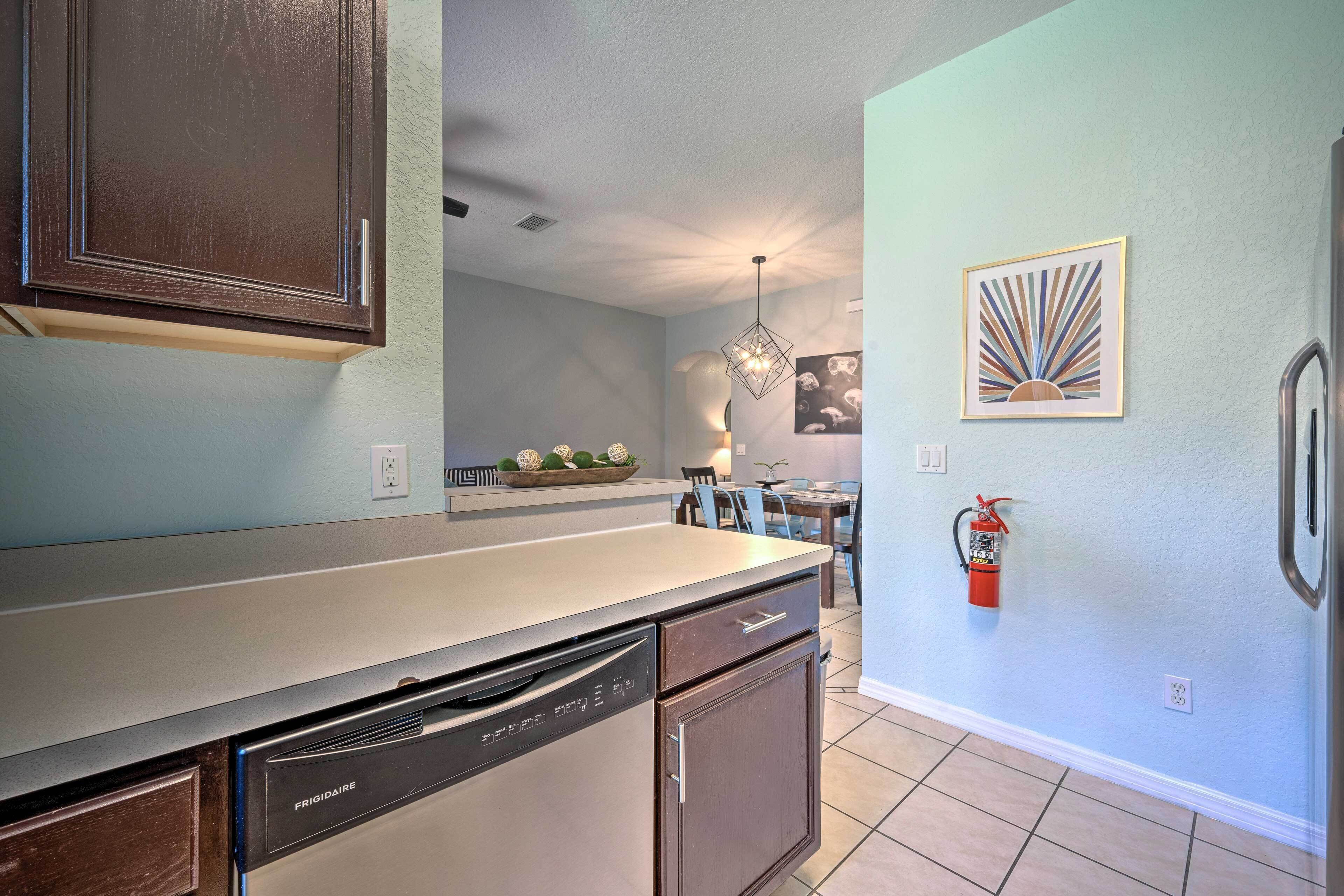 A kitchen with a dishwasher, cabinets, and a fire extinguisher on the wall.