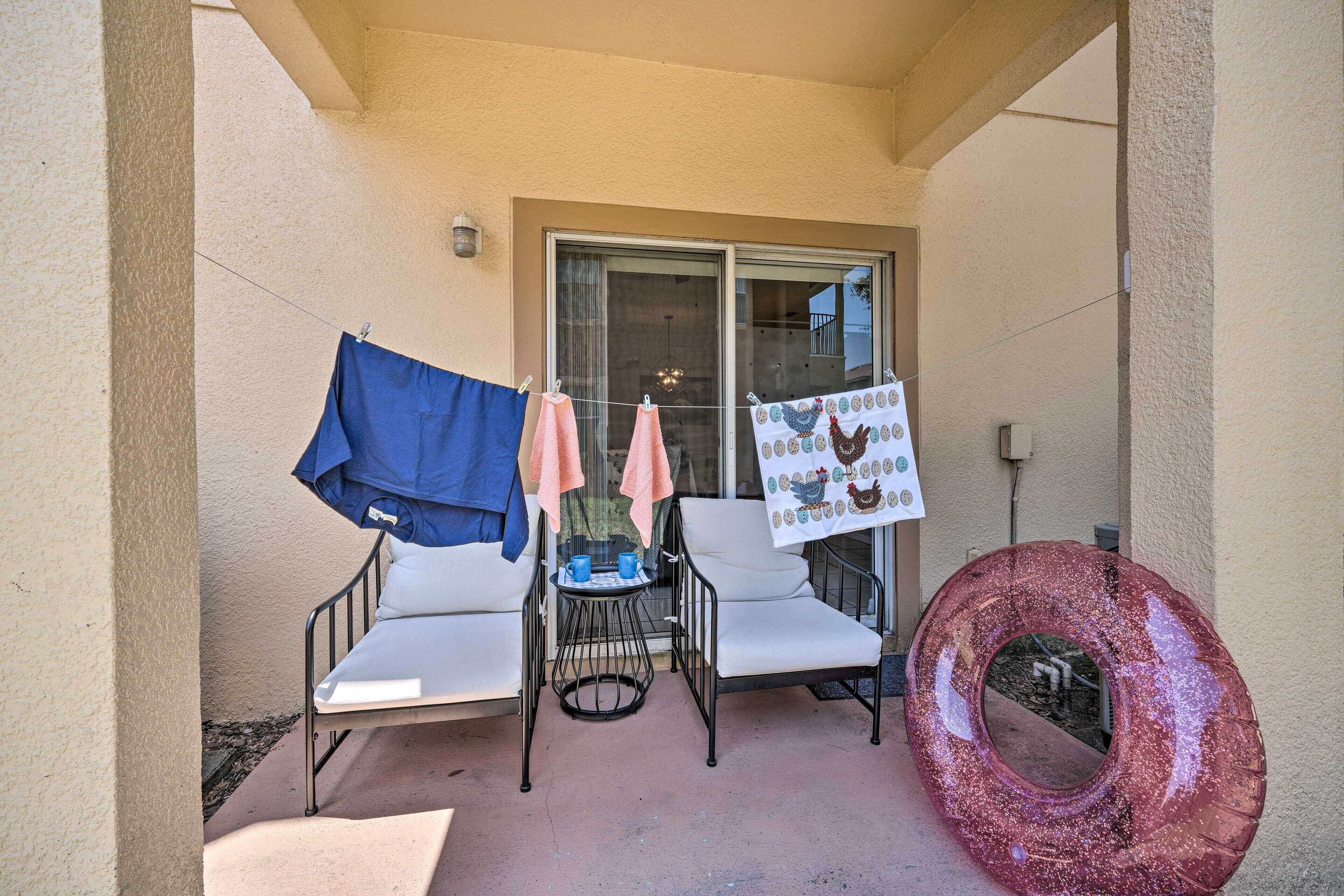 A balcony with two white chairs, a small table with blue cups, and a red inflatable ring.
