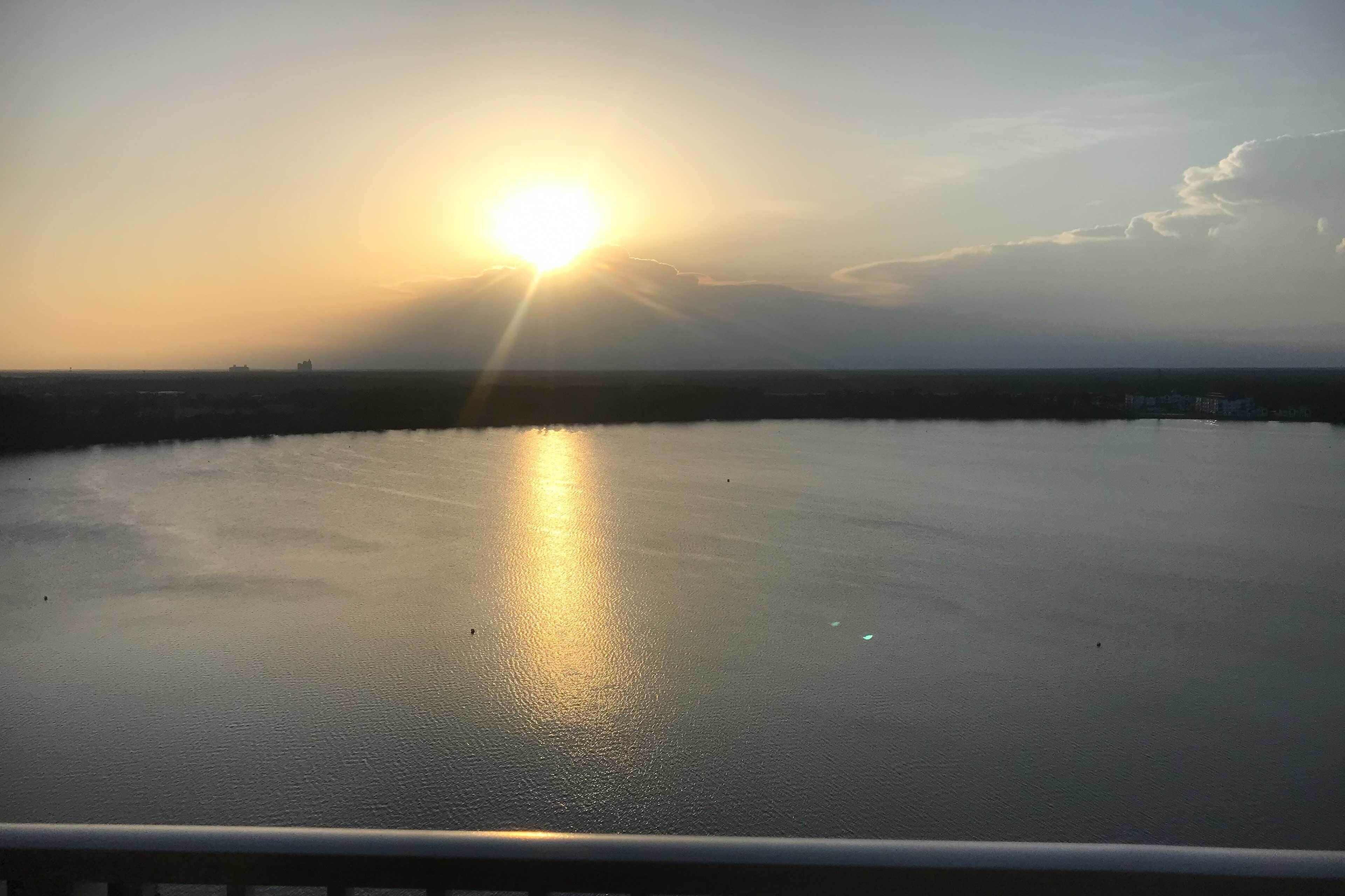 A calm body of water reflecting the sun, with a distant shoreline and a clear sky.