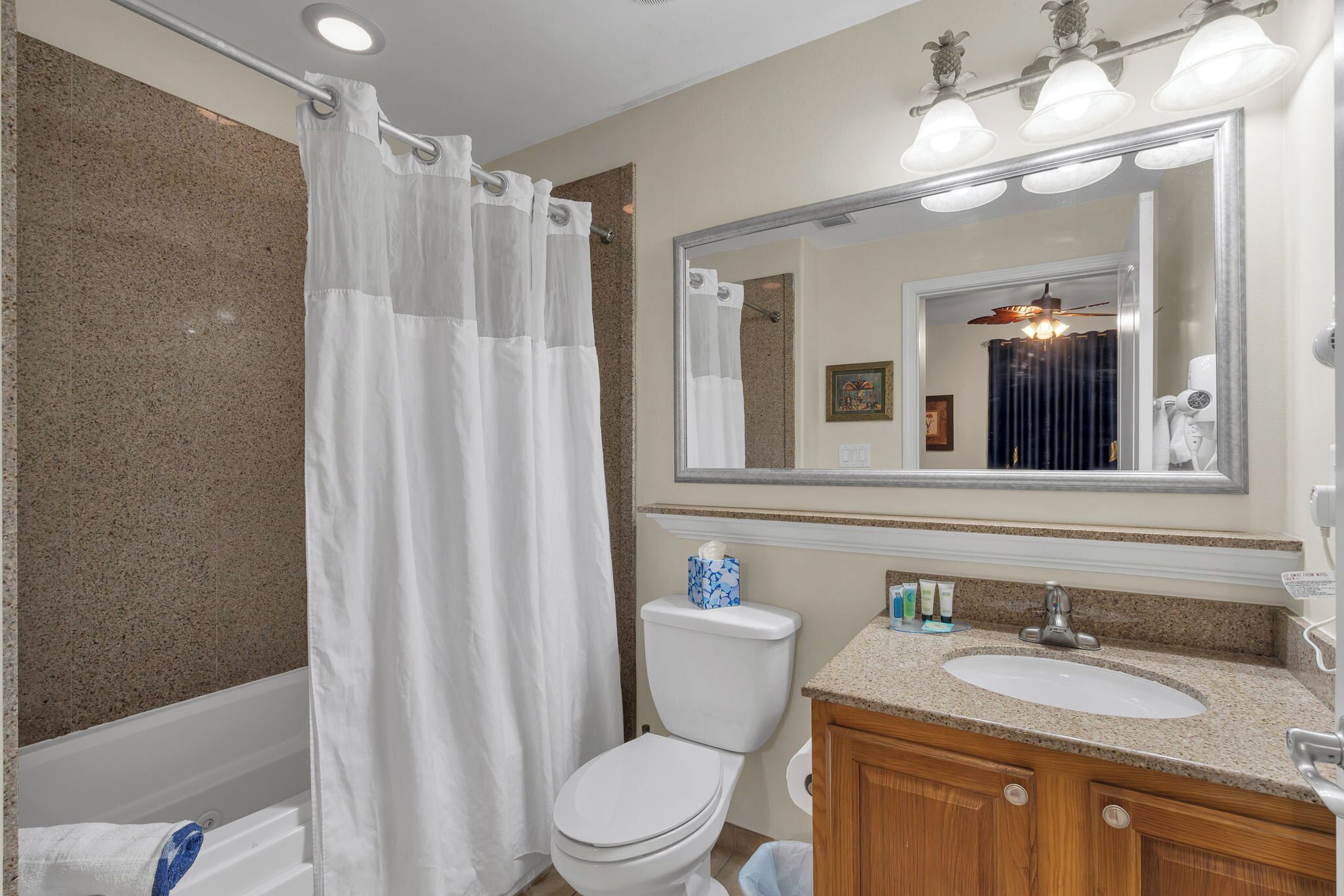 Une salle de bain équipée d’un rideau de douche, de toilettes, d’un lavabo et d’un miroir.