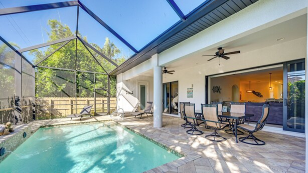 Ein Schwimmbad mit Glasveranda, Sitzgelegenheiten im Freien und einer überdachten Terrasse.