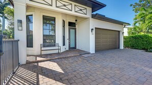 Ein modernes Haus mit Garage, einer Veranda mit Bank und einem gepflasterten Einfahrt.
