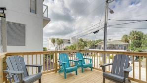 A wooden deck with two Adirondack chairs and a table, overlooking a residential area with houses and trees. - Coastal 'sea Side' Townhome - Walk to Beach! (Clearwater Beach)