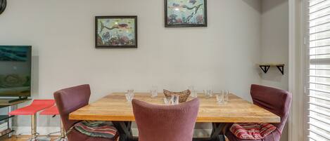 A dining area with a wooden table, four chairs, and two framed pictures on the wall.