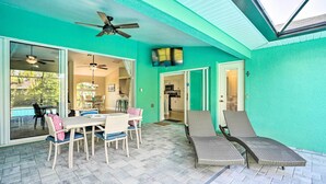 A covered patio with a dining table and chairs, a ceiling fan, and a TV mounted on the wall. - Colorful Cape Coral Vacation Rental w/ Pool! (Cape Coral)