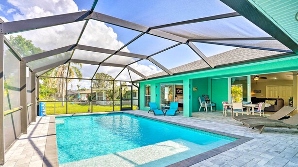 A swimming pool with a glass enclosure, surrounded by a patio area with chairs and a table. - Colorful Cape Coral Vacation Rental w/ Pool! (Cape Coral)