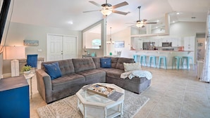 A spacious living area with a sectional sofa, a glass coffee table, and a kitchen in the background. - Colorful Cape Coral Vacation Rental w/ Pool! (Cape Coral)