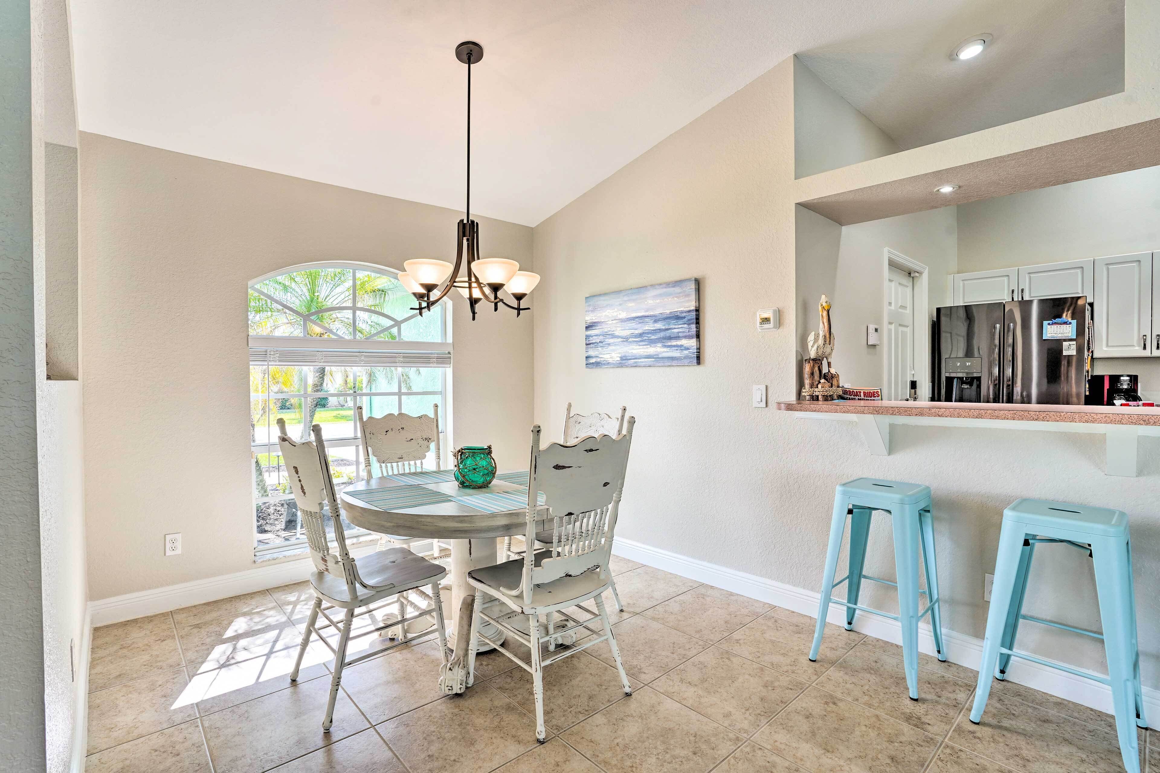 A kitchen with a dining area, a chandelier, and a view to the outside.