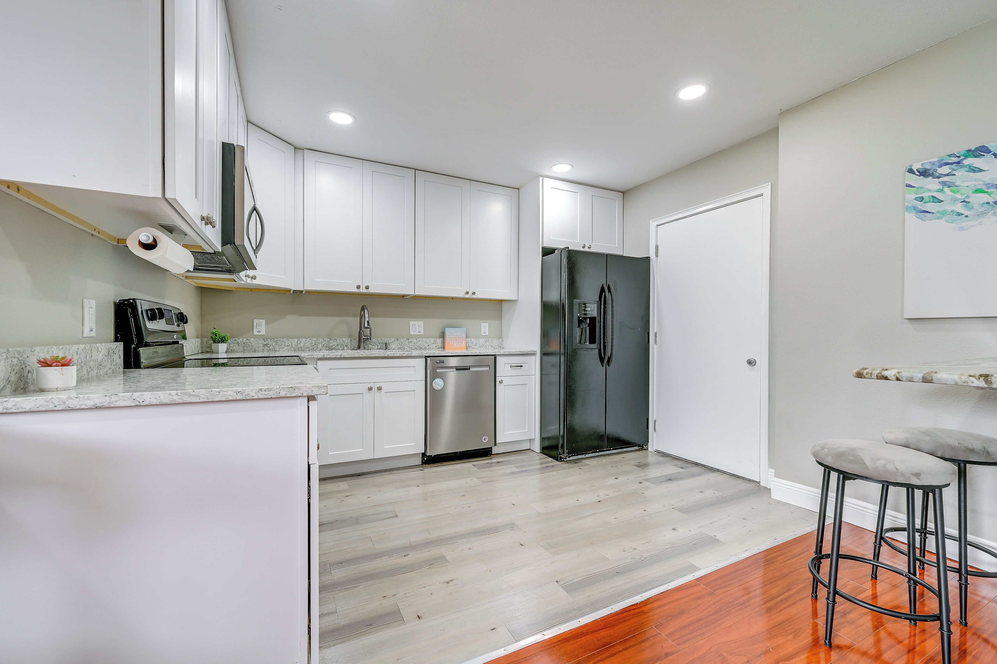 A modern kitchen with white cabinets, a stainless steel refrigerator, and a dishwasher.