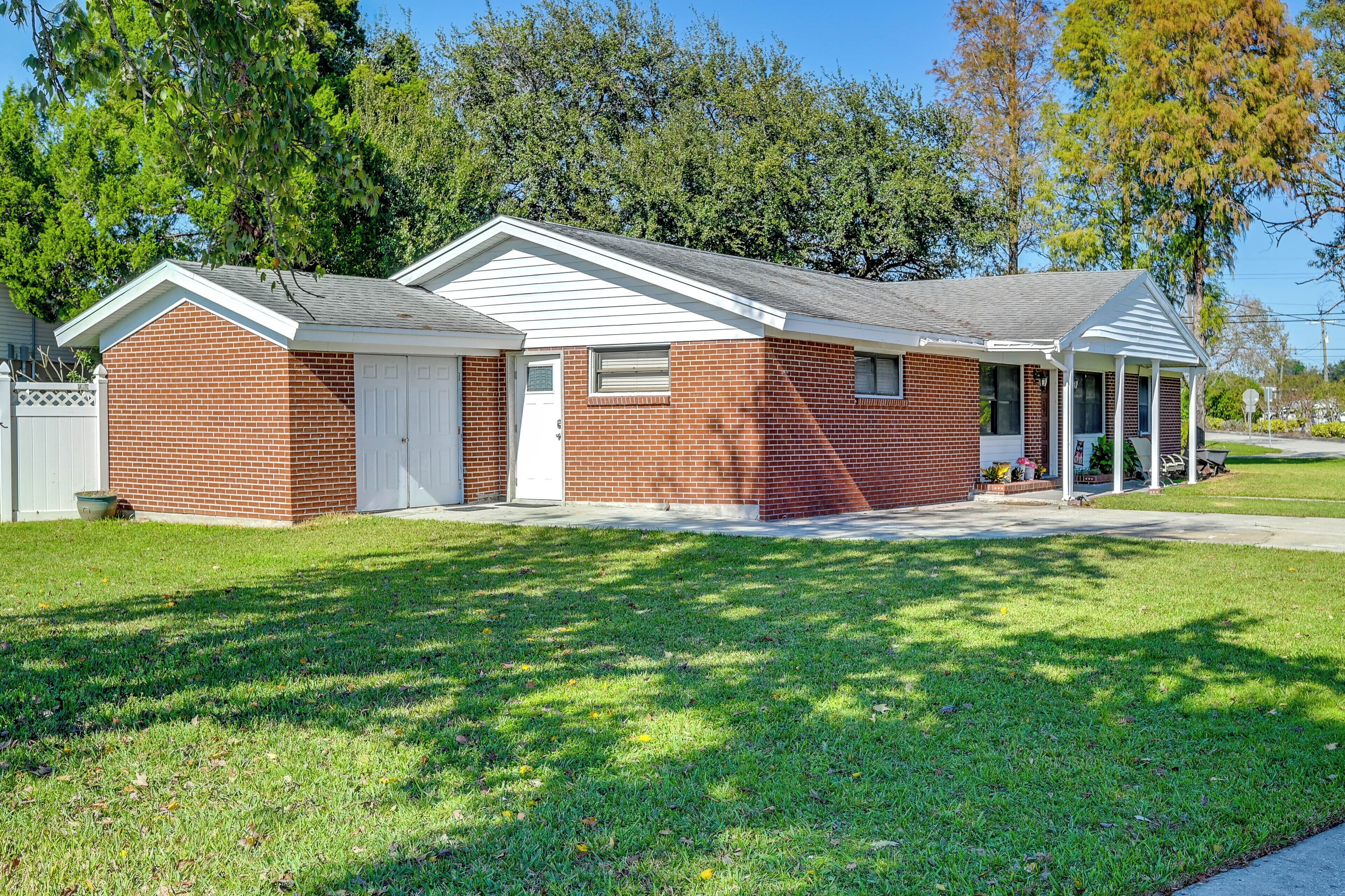 A single-story brick house with a white garage door, a covered porch, and a small front yard.