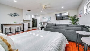Une chambre d’hôtel moderne avec un grand lit, un canapé gris et un petit coin repas.