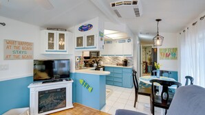 A modern kitchen with blue cabinets, a central island, and a dining area with a table and chairs. - Resort Pool & Sports Courts! Port Charlotte Home (Port Charlotte)