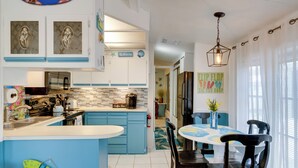 A modern kitchen with blue cabinets, a coffee bar, and a dining area with a round table and chairs. - Resort Pool & Sports Courts! Port Charlotte Home (Port Charlotte)