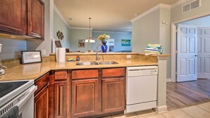 A kitchen with wooden cabinets, a white dishwasher, and a granite countertop. - 10 Mi to Disney: Davenport Condo w/ Pool Access! (Davenport)