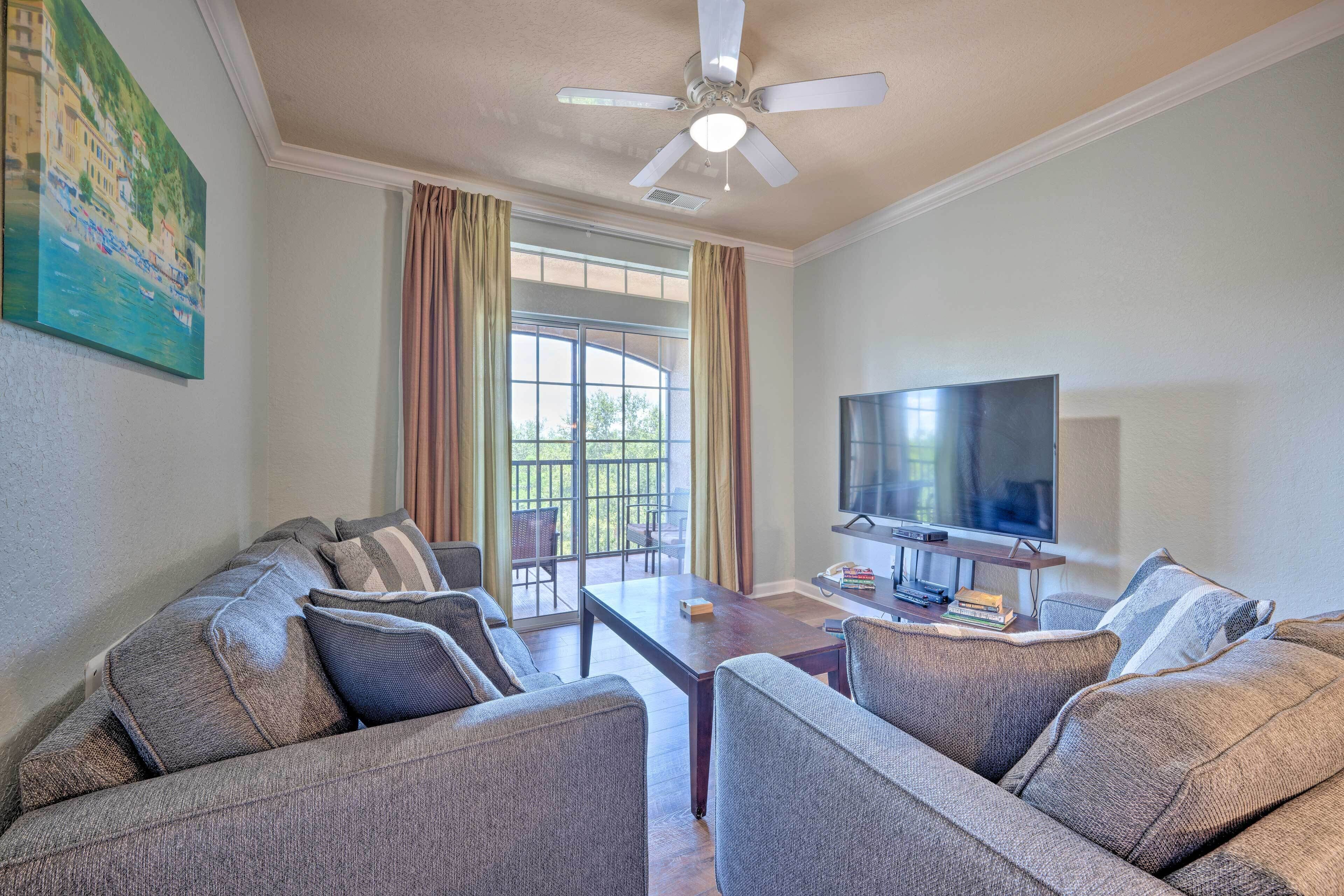 A living room with a sofa set, a flat-screen TV, and a ceiling fan.