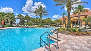 A swimming pool with a metal ladder, surrounded by palm trees and lounge chairs. - Private Pool + Game Room Near Disney & Parks (Davenport)