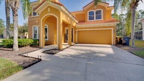 A two-story house with a yellow facade, a red-tiled roof, and a garage. - Private Pool + Game Room Near Disney & Parks (Davenport)
