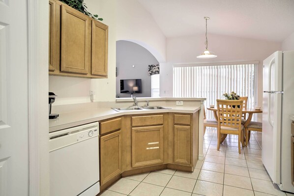 A kitchen with wooden cabinets, a built-in oven, and a dining area with a table and chairs.