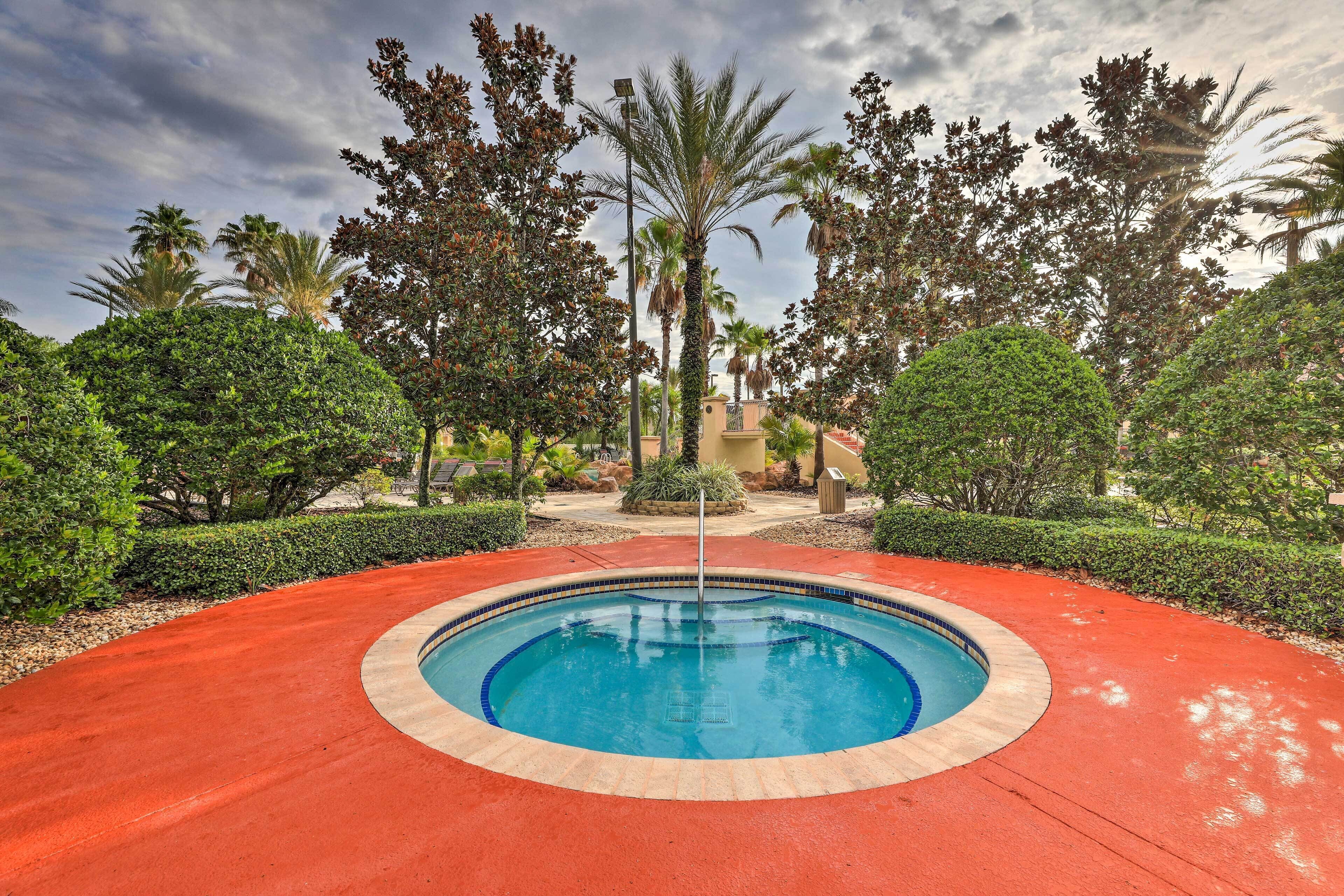 A circular pool with a red border, surrounded by well-maintained greenery and palm trees.